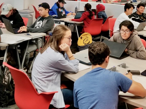 students working on laptops in a large collaborative learning classroom