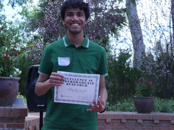 Abhi displays his Excellence in Undergraduate Research certificate