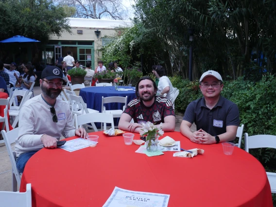 3 event attendees at a table with a red cloth
