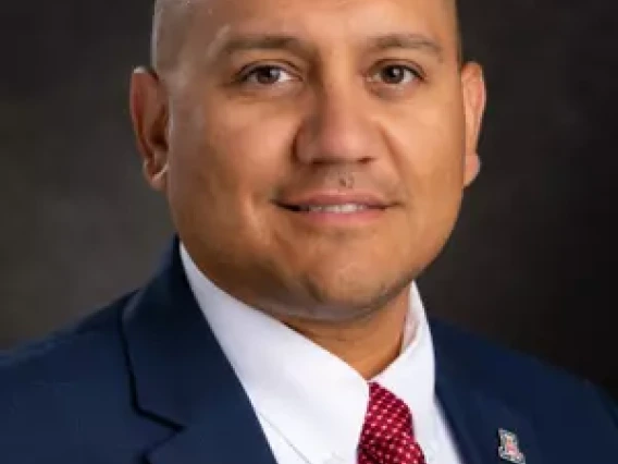headshot of mario in blue suit jacket white shirt and red tie