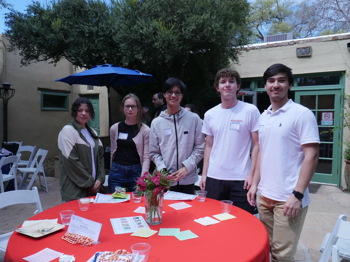 5 CS ambassadors stand t a table with a red cloth