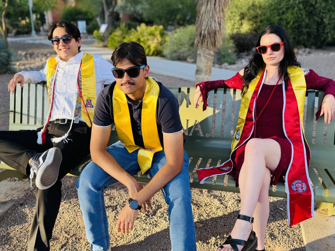 students sitting casually in grad regalia
